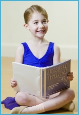 Photo of junior ballet ballerina looking at a book